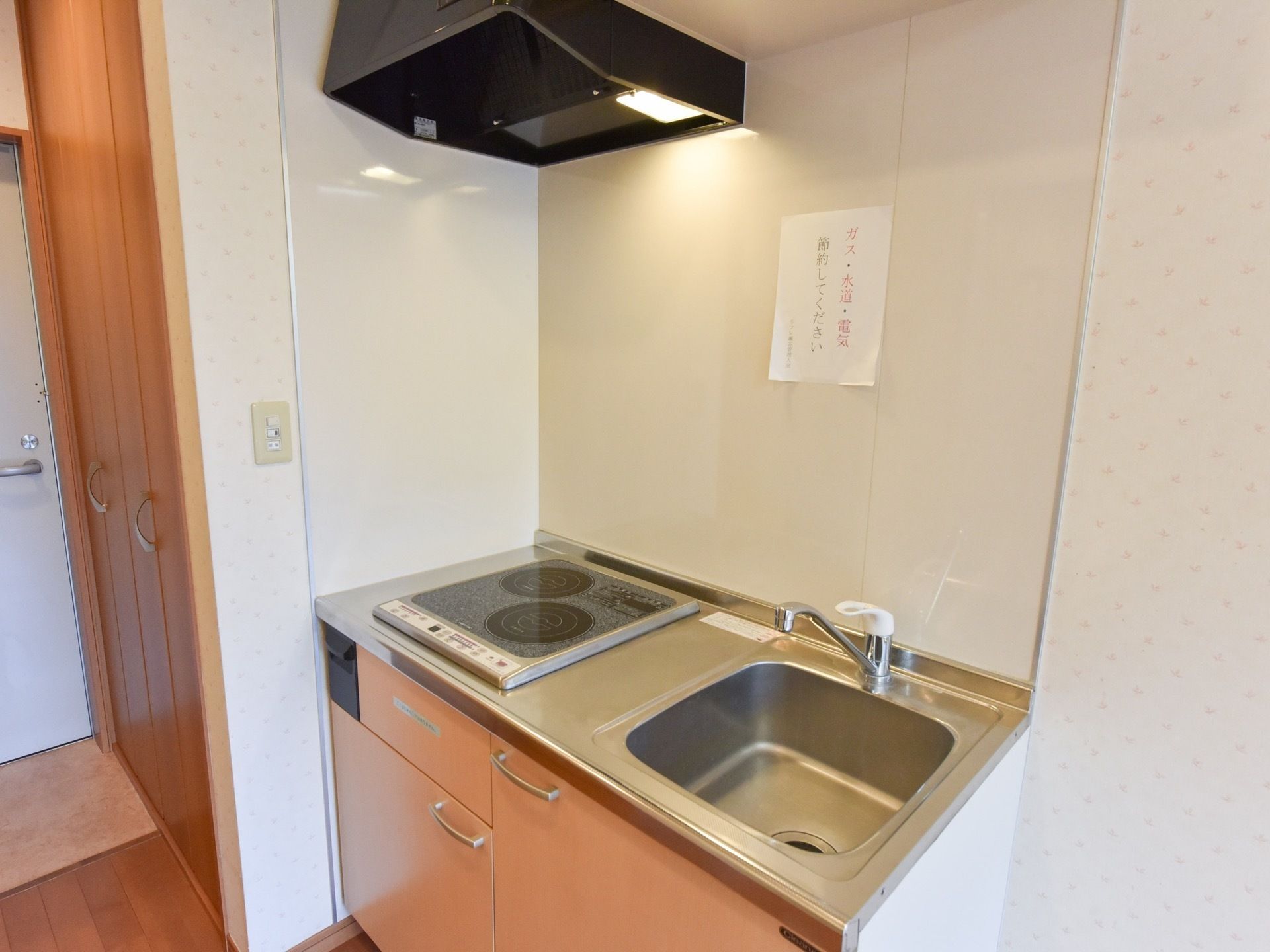 流しと2口の電磁調理台が付いたミニキッチンがある。台の部分には収納があり、食器や調理器具をしまっておける。