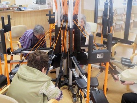 オレンジと黒のトレーニング機器でトレーニングをしている高齢者