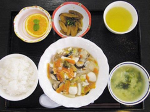 ごはん、あんかけ、スープ、オレンジ、小鉢、お茶が乗っているトレー