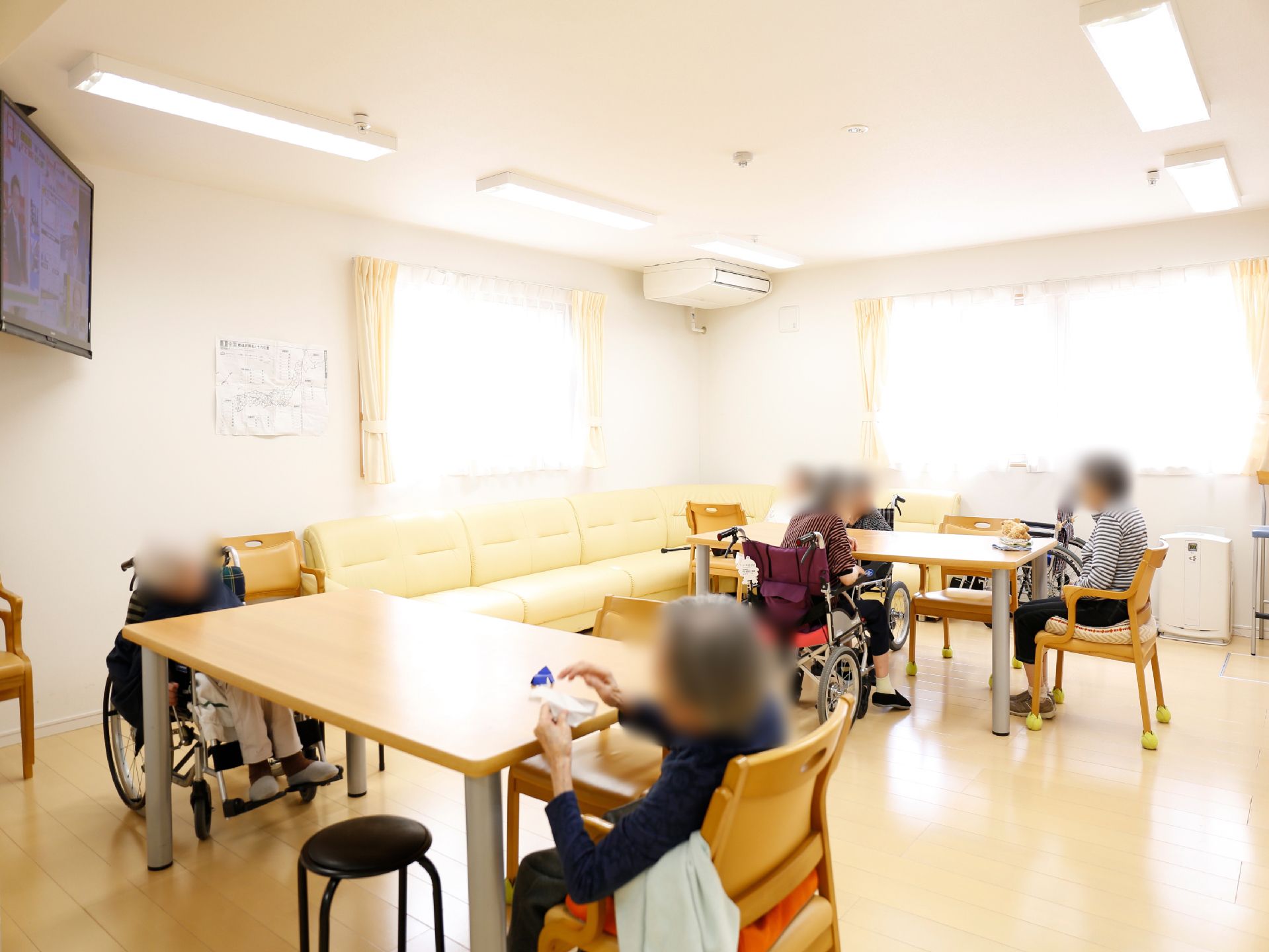 リビングとして利用される共有スペース。大きなテーブルに座席が設けられ、部屋の角には大きなＬ字型のソファが置かれている。