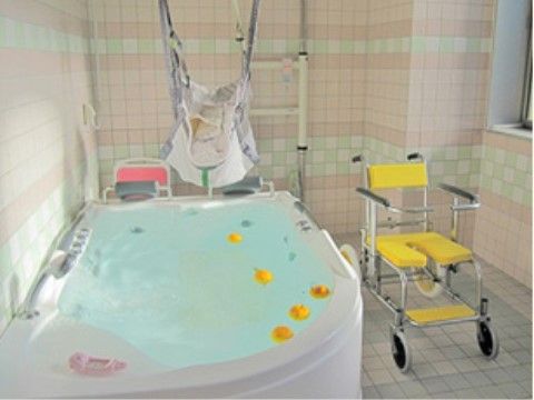 タイル張りの浴室に介護浴槽が設置され、柑橘類が浮かべられている。洗い場には黄色いシャワー椅子がある。
