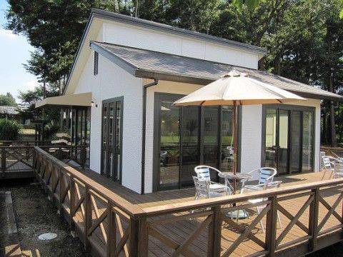 窓がたくさん取り付けられた平屋建ての建物である。建物の周りにウッドデッキが設置され、パラソルと椅子が置いてある。