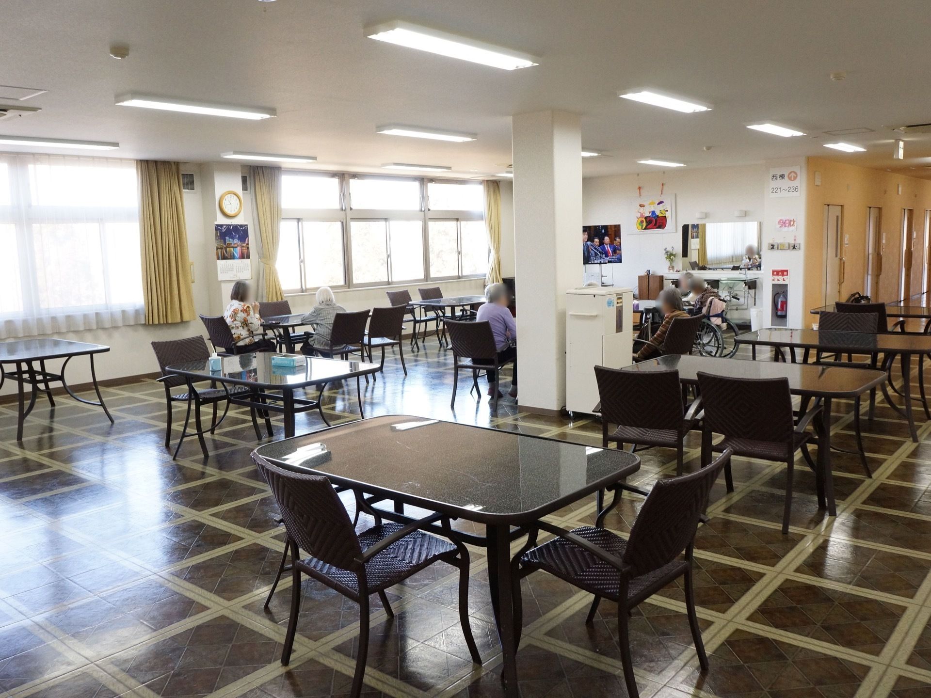レースのカーテン越しに明るい光が差し込み、格子模様の床が白く輝いている。窓の横の柱には、丸い形の時計が掛けてある。