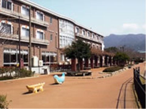 外に動物の遊具が二つある、洋風な老人ホームの施設外観