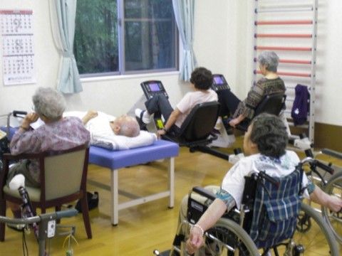 トレーニング機器でトレーニングする入居者や、車椅子の人がいる共有スペース