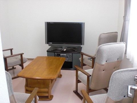 白を基調とした空間。壁際に設置されているテレビに向かって、一人掛けのソファチェアがいくつも配置されている。