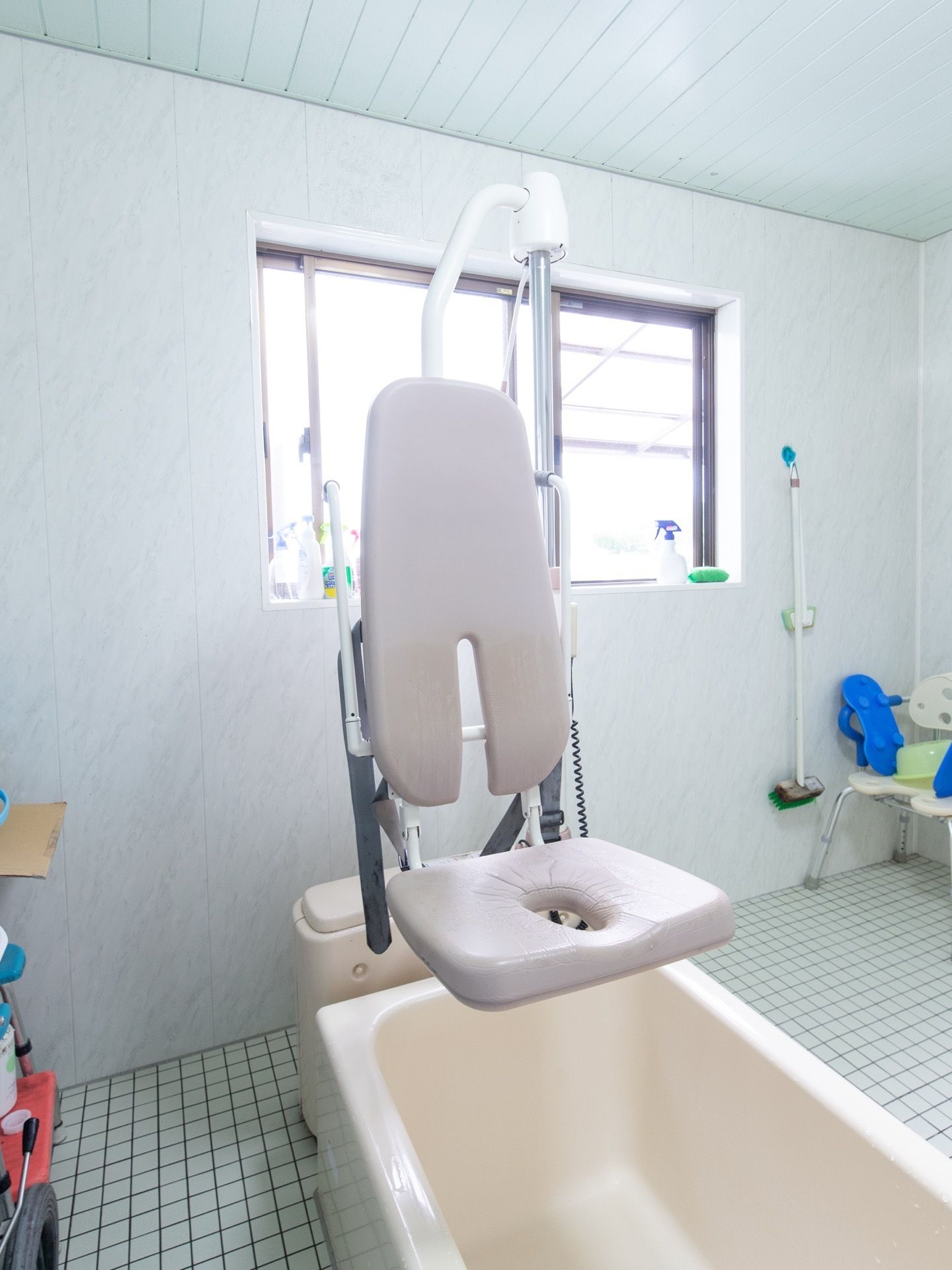 小窓のある明るく開放的な介護浴室である。座ったままの姿勢でも入浴できるよう、リフトが設置されている。