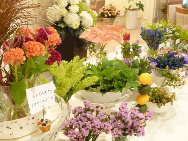 ガラスの器や植木鉢などに飾られたオレンジやピンクの花