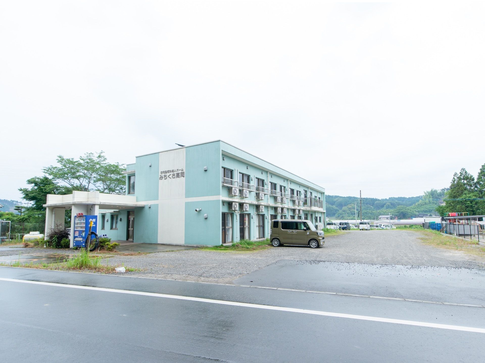 2階建ての集合住宅のような外観の建物が広い敷地に建てられている。外装は明るい色合いになっていて、柔らかい印象。