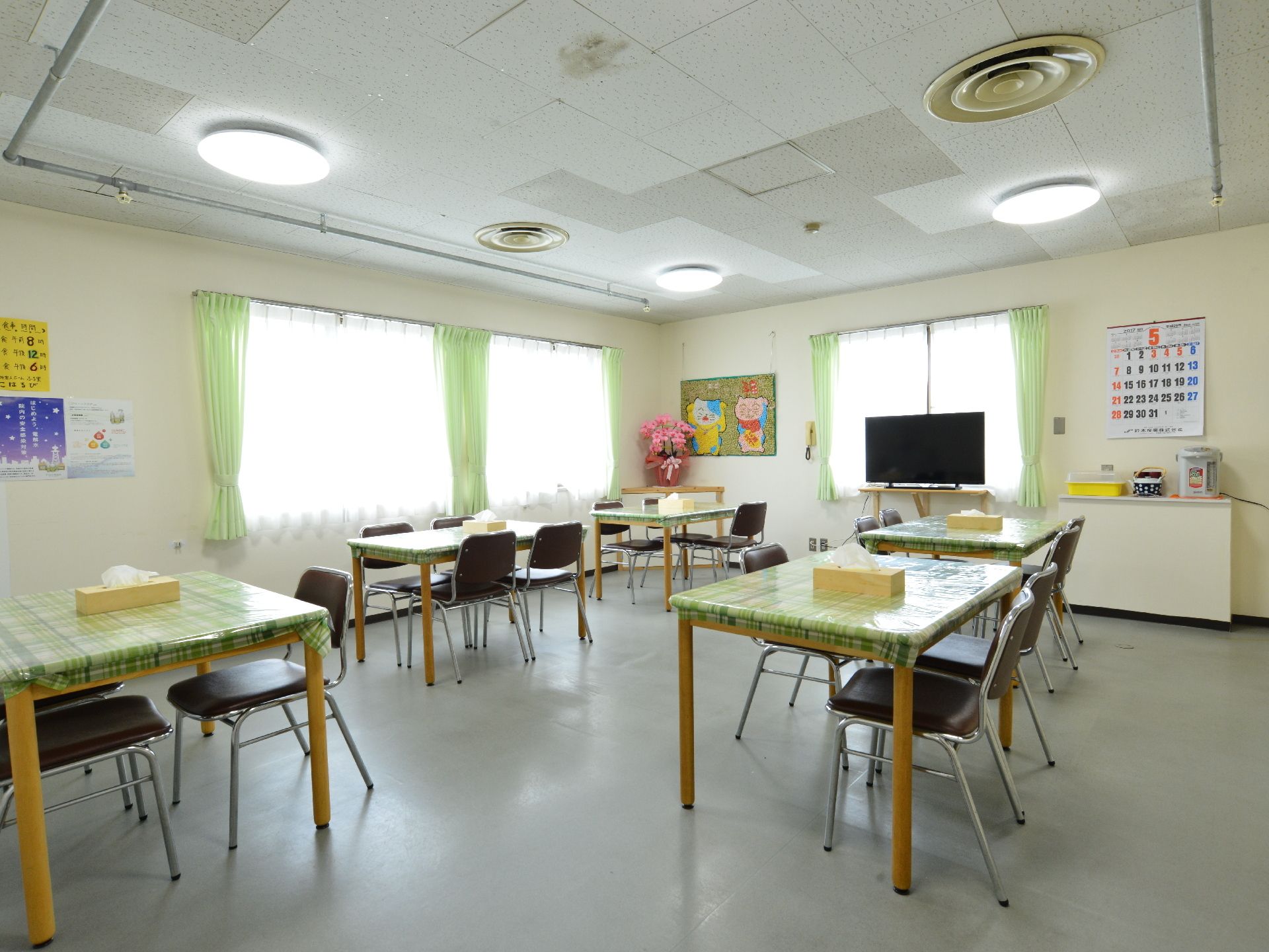 緑のチェックのテーブルクロスがかけられた机が並ぶダイニング
