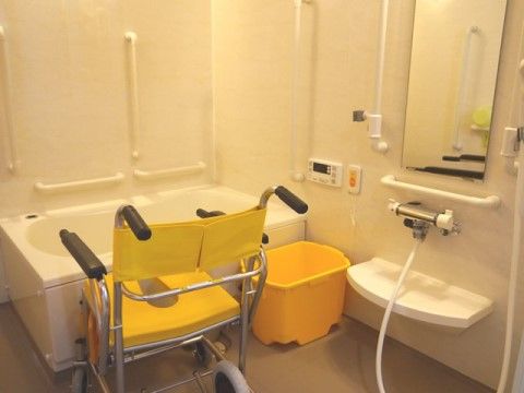 車椅子のまま入ることができる広い浴室である。壁には、立ち座りを補助するための手すりが縦向きと横向きに設置されている。
