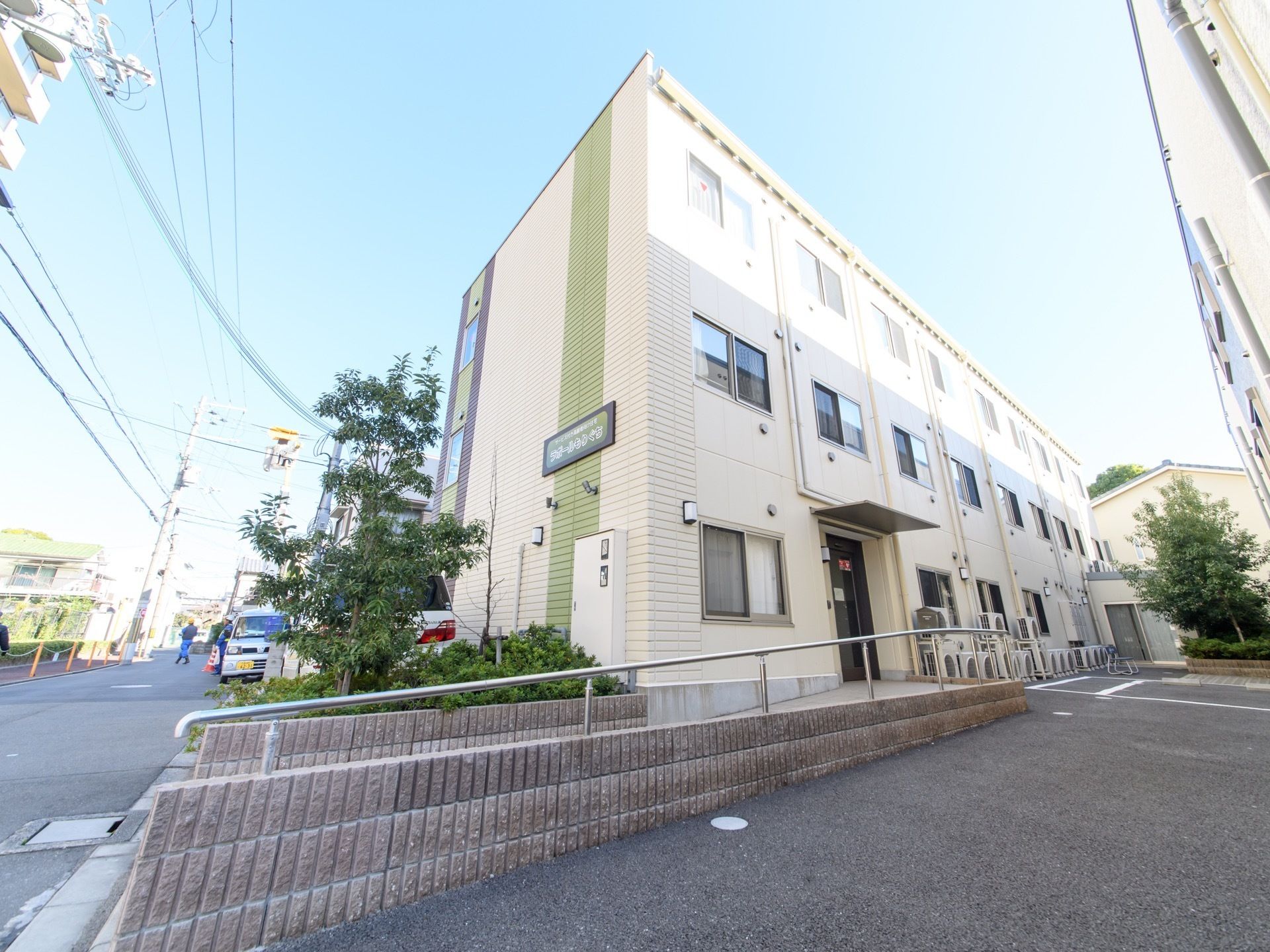 クリームと緑ベースの明るい配色の施設の外観。住宅街の中に立っているので、騒音などの問題がなく、夜もゆっくり安心して眠れる。
