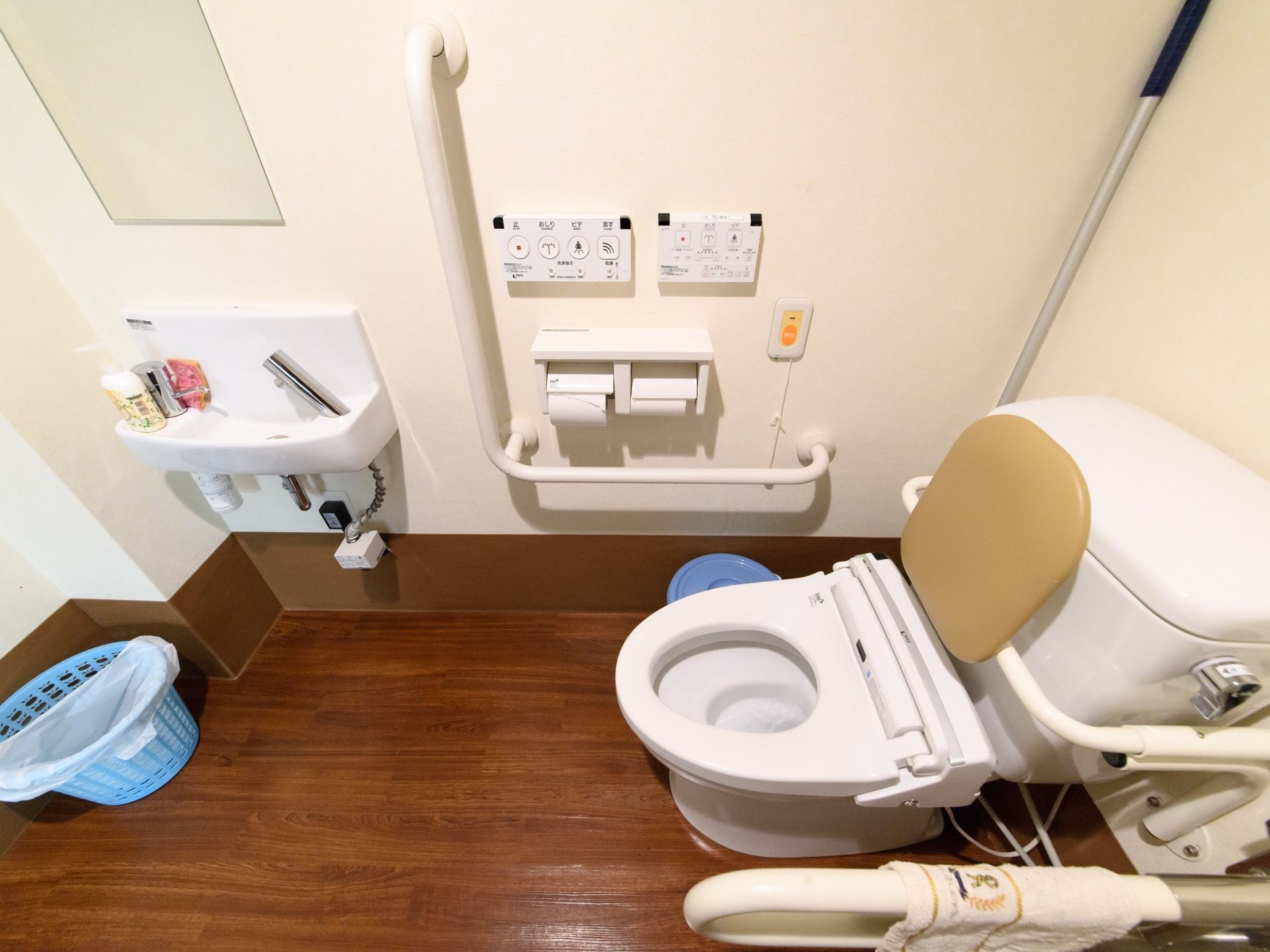 洋式トイレの便座の両脇には、立ち座りを補助する手すりが設置されている。洗面台には大きな鏡が付いており、身だしなみを整えるのに便利である。