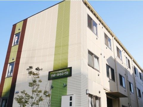 外壁に緑の板でできた施設名の看板が取り付けられている施設