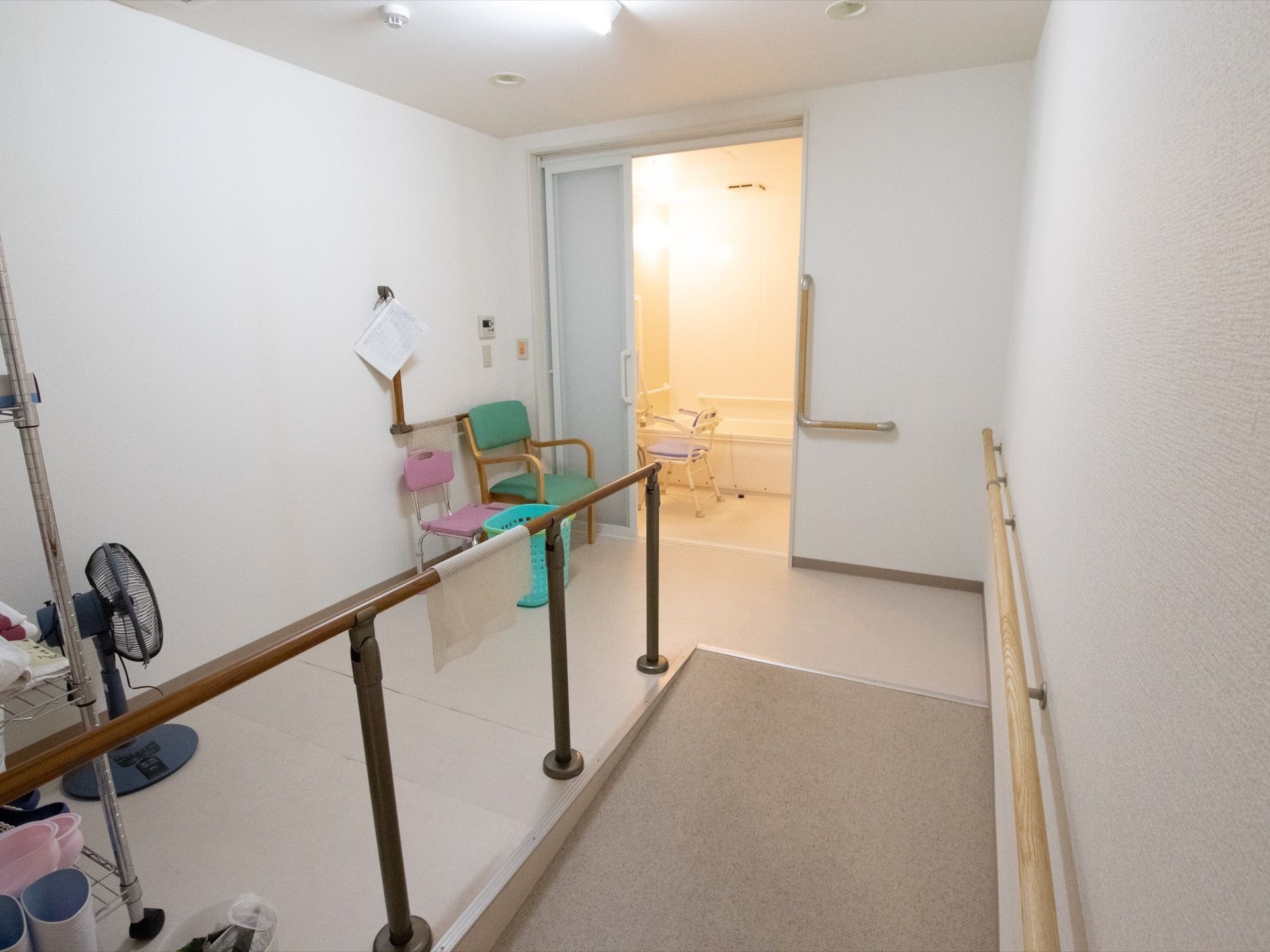 浴室に向かってスロープがあり、手すりが両側に設置されている。浴室用の介護用椅が浴室内外に２脚用意されている。