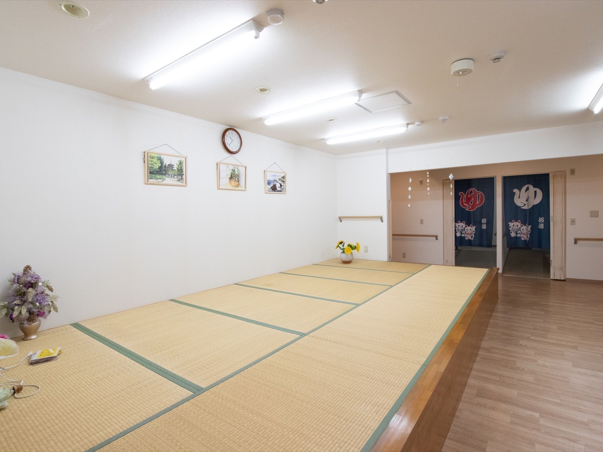 ゆの字ののれんがかけられた浴室への入口が奥にある広間