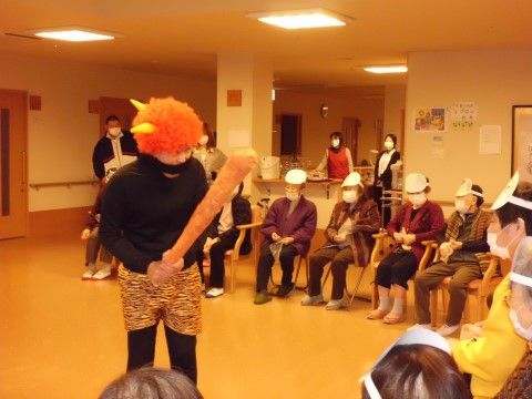 鬼のかっこをしたスタッフの周囲に半円形に座っている入居者様