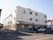 ３階建ての建物で、入口前に階段とスロープがある。自動販売機が置かれている。施設前は歩道がついている。