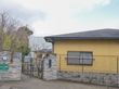 高齢者が暮らす居住施設の建物は、平屋建てとなっている。また入り口の門には看板があり、照明器具と郵便受けが設置されている。