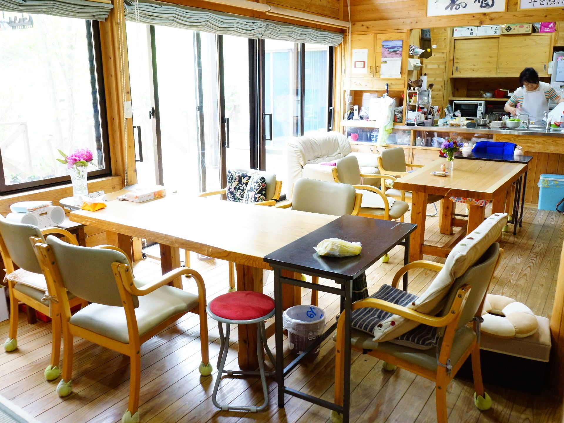 たくさんのテーブルセットの奥にあるキッチンで作業をするスタッフ