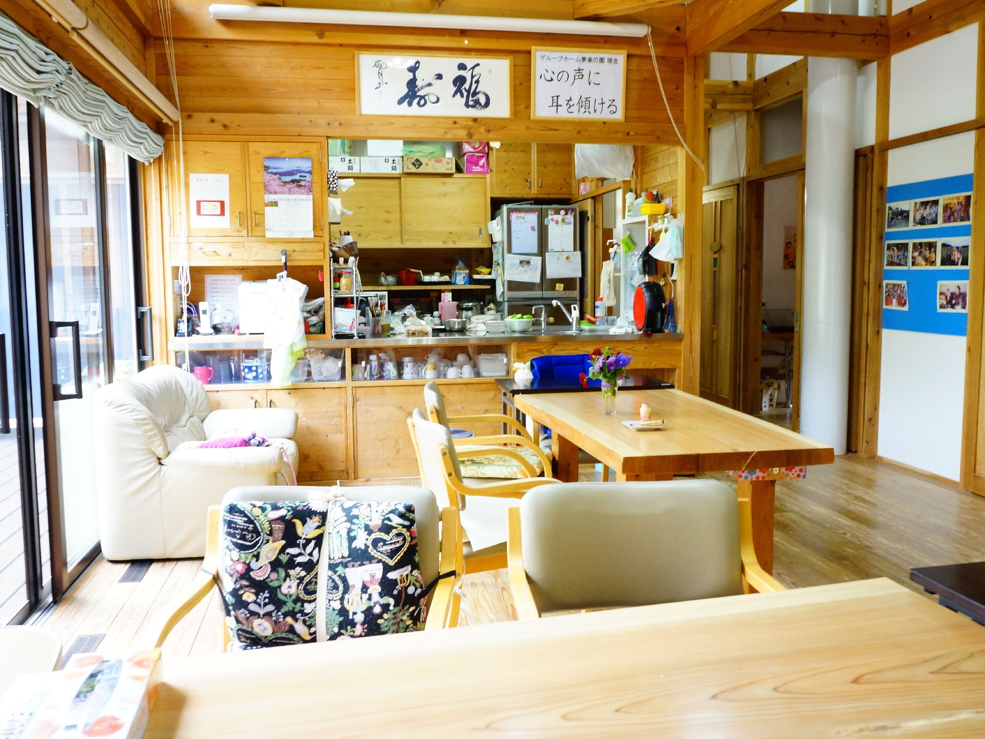温かみのある木造建築物のリビング。大きな窓があり、その窓からは柔らかな光が差し込む。ゆったりと過ごすことができる。