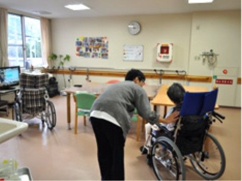 車椅子でうたた寝をする入居者様に声をかけているスタッフ
