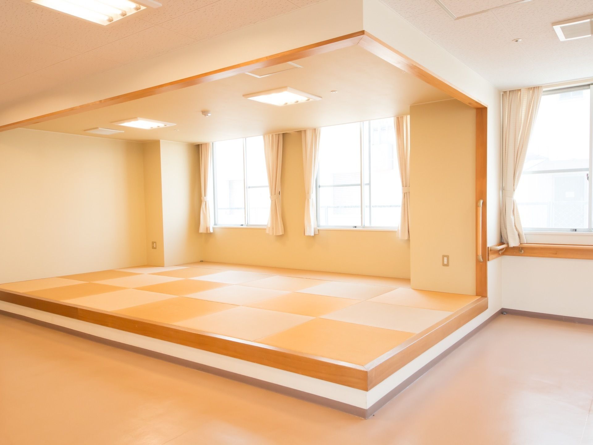 明るく清潔に整えられた室内の一角に、畳の小上がりがある。壁の要所に手すりが設置され、各窓にはカーテンがかけられている。