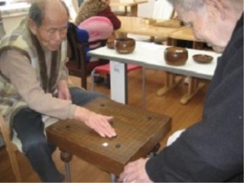 仲のいい入居者様と椅子に座って囲碁を楽しんでいる２人の男性
