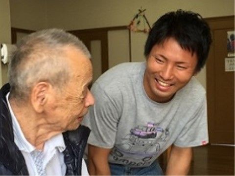 男性入居者様に声を掛けて微笑んでいるグレーのTシャツのスタッフ