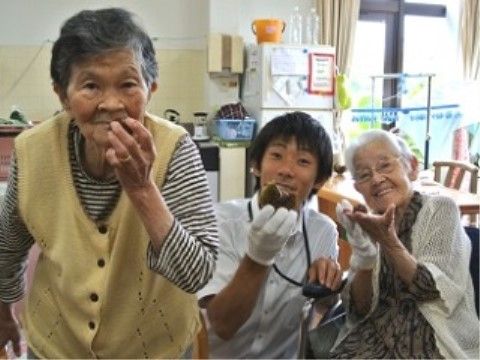 手にお菓子を持ってカメラに向かってポーズを取るスタッフと入居者様