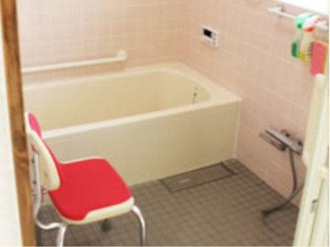 個室タイプの浴室である。バスタブ横の壁に手すりが設置されており、洗い場にはシャワーチェアが置かれている。