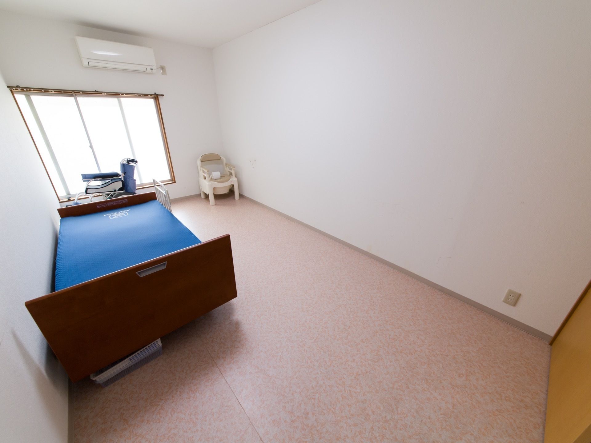 青いマットレスが乗せられた介護用ベッドが備え付けられた部屋