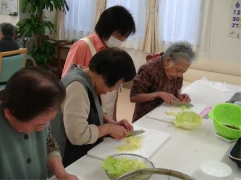 スタッフのサポートを受けながら、レタスを切っている入居者様