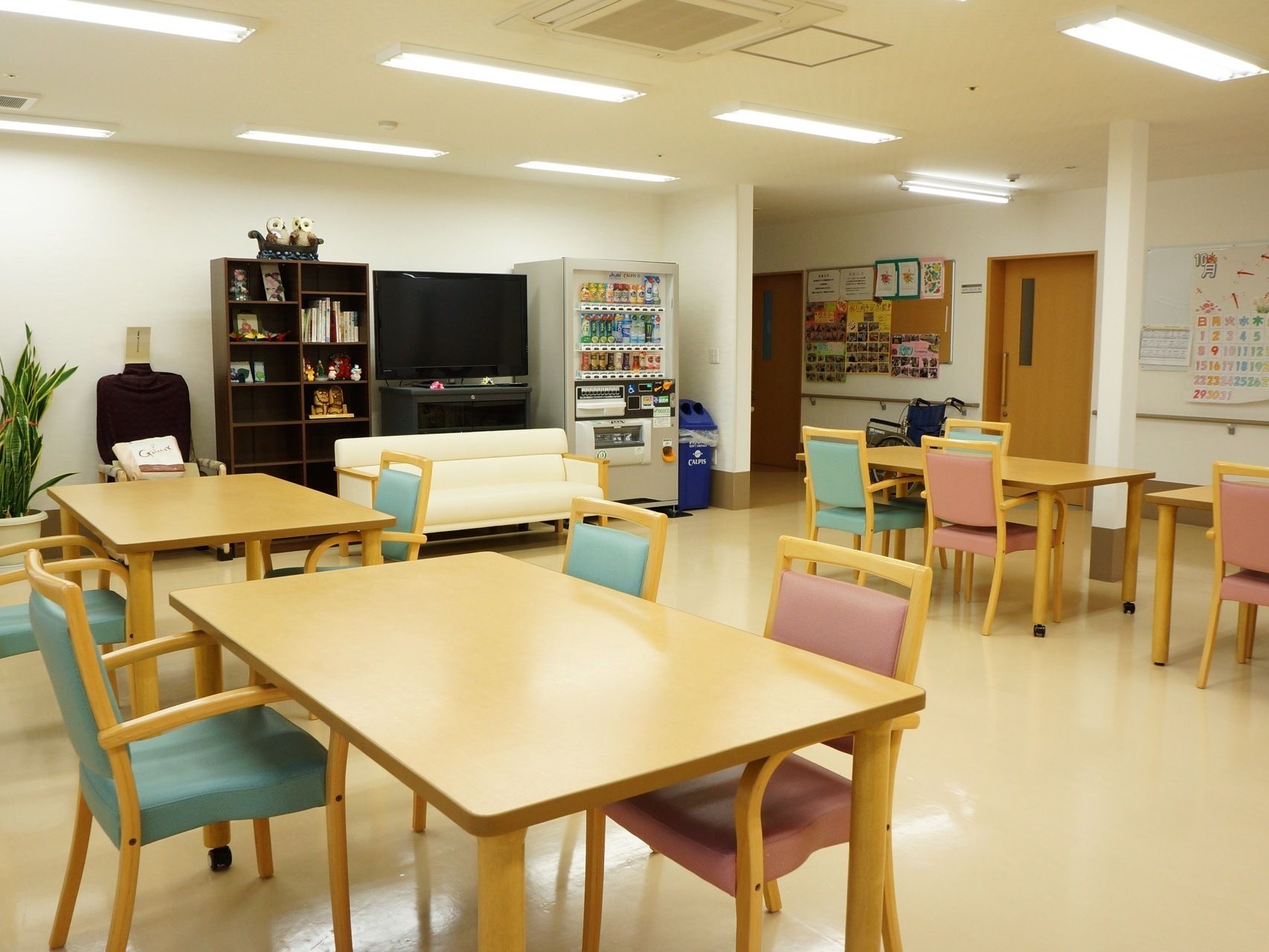バリアフリーに配慮された開放的な共有スペース。壁際には大型のテレビと本棚、自動販売機が備わっている。空調も完備されている。