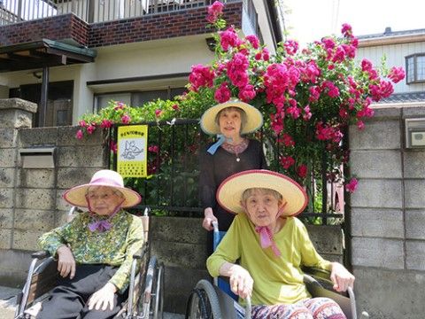 ブロック塀を越えて咲くブーゲンビリアの花の前の入居者様