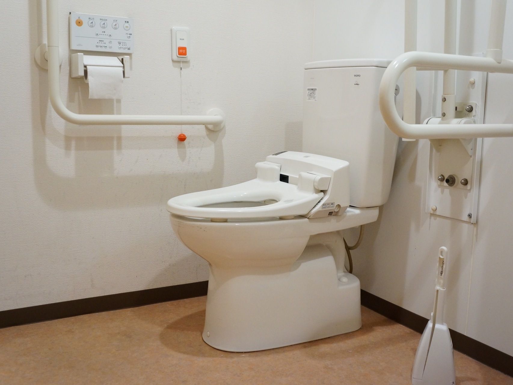 トイレには便座と男性用小便器が設置されている。壁際にはトイレットペーパーと温水洗浄便座の操作ボタンがある。
