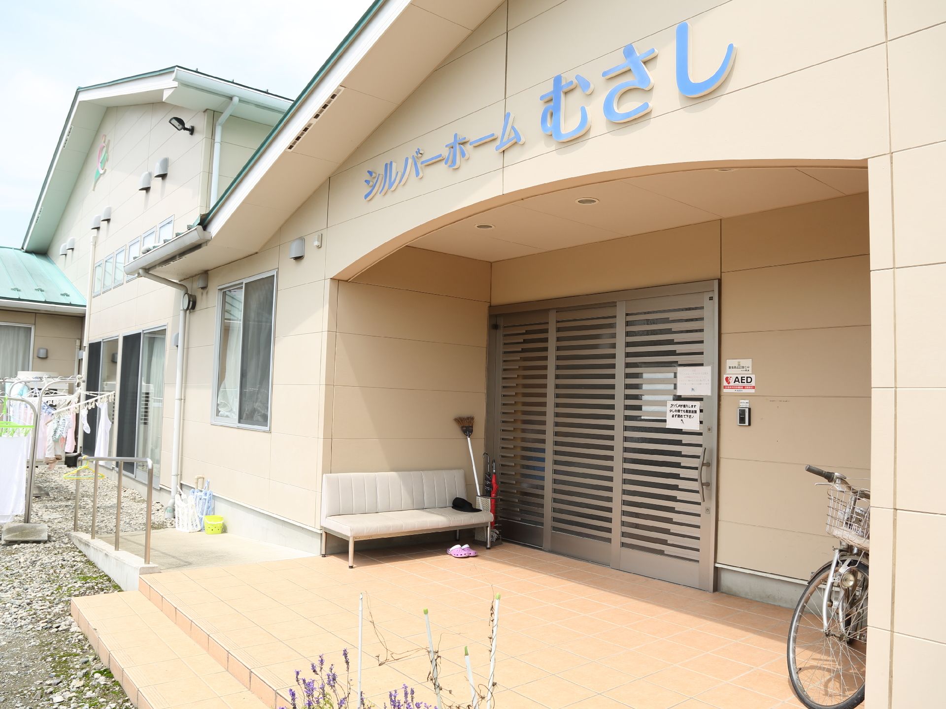 入り口周辺の様子。ソファや自転車が置かれている。左側のスペースには、物干しざおが設置され、入り口に向けてスロープがある。