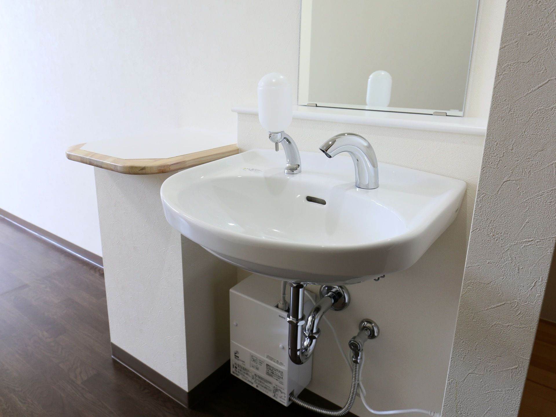 居室備え付けの洗面台。蛇口のほかに石けん用ポンプが取り付けてある。横には小物を置ける棚が設置されている。