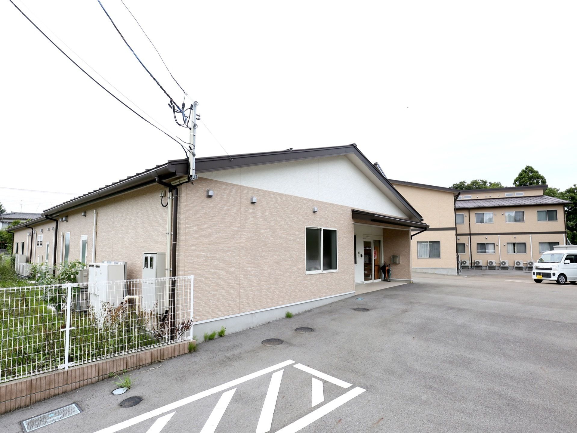 建物は入居用住宅とデイサービス施設で分かれている。敷地は全面アスファルト舗装で、広い駐車場を備えている。