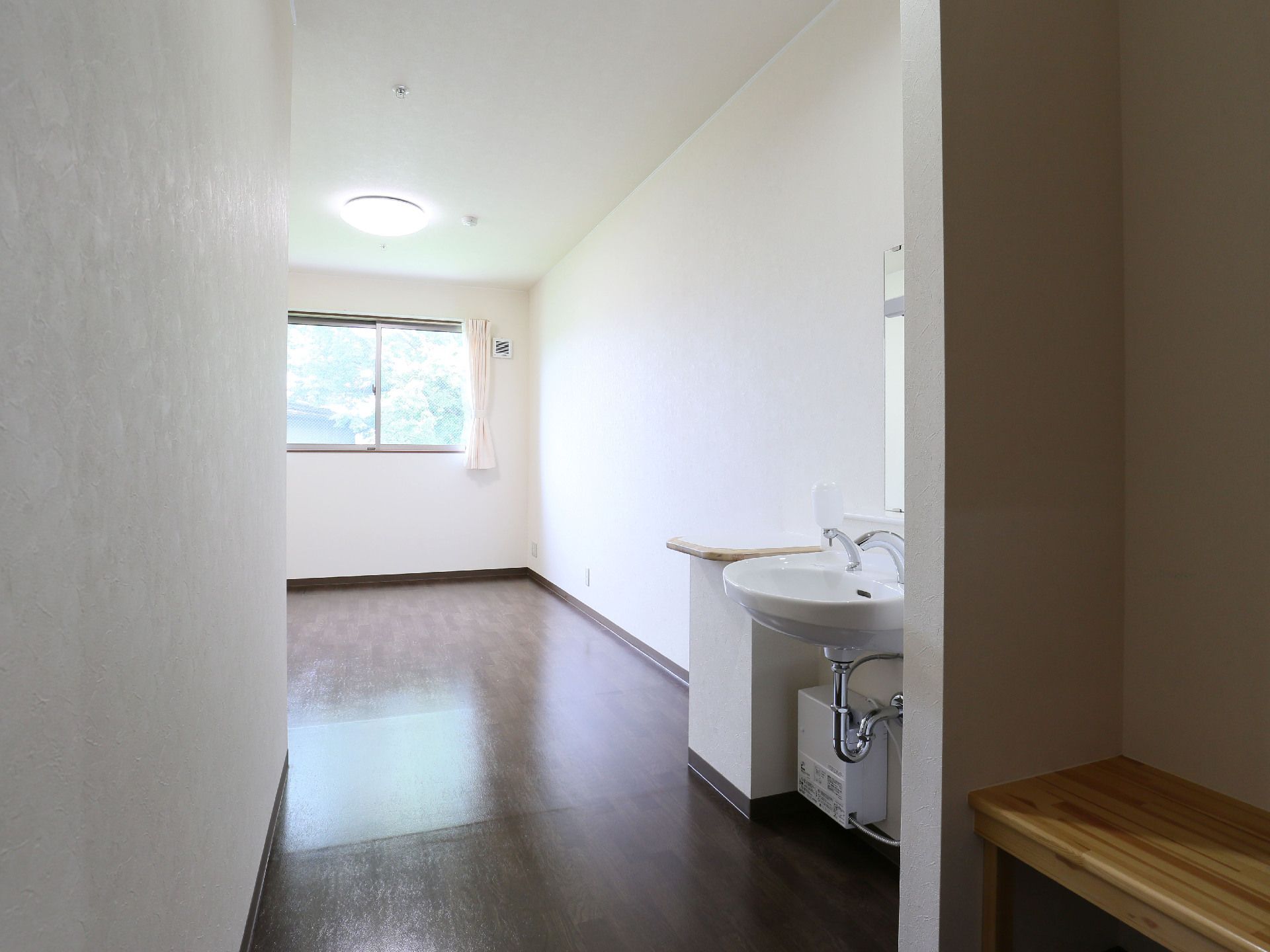 カーテンが開いた窓が奥に見えている、廊下側からみた居室内部