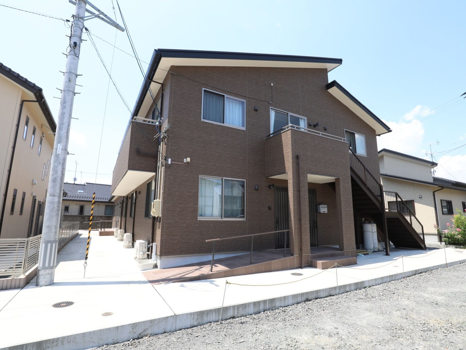 ２階部分にベランダが設けられている。非常階段が設置されており、目の前の道には小さな砂利が敷かれている。