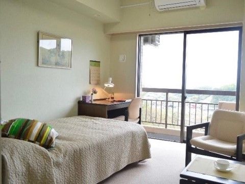 窓の外に緑で覆われた山や近隣の住宅地が見えている部屋