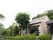 緑豊かな敷地内に４階建ての施設が建っている。左奥に駐車場が設けられている。エントランスには、ひさしが付いている。