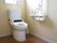 トイレの様子。ウォシュレット機能がついており、一般的な家庭用の洋式水洗トイレが設置されている。ペーパーホルダーの上には手すりがついている。