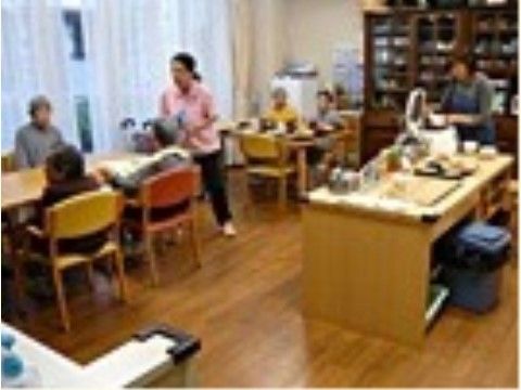 テーブルの周囲にある椅子に腰かけてスタッフと話をする入居者様