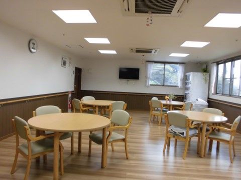 広い食堂には、３人掛けのテーブルが配置されている。左右の壁には、手すりが取り付けられている。自販機が設置されている。