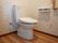 トイレットペーパーホルダーが２つ壁に設置されている。壁に１口のコンセントがある。室内は広くスペースが確保されている。