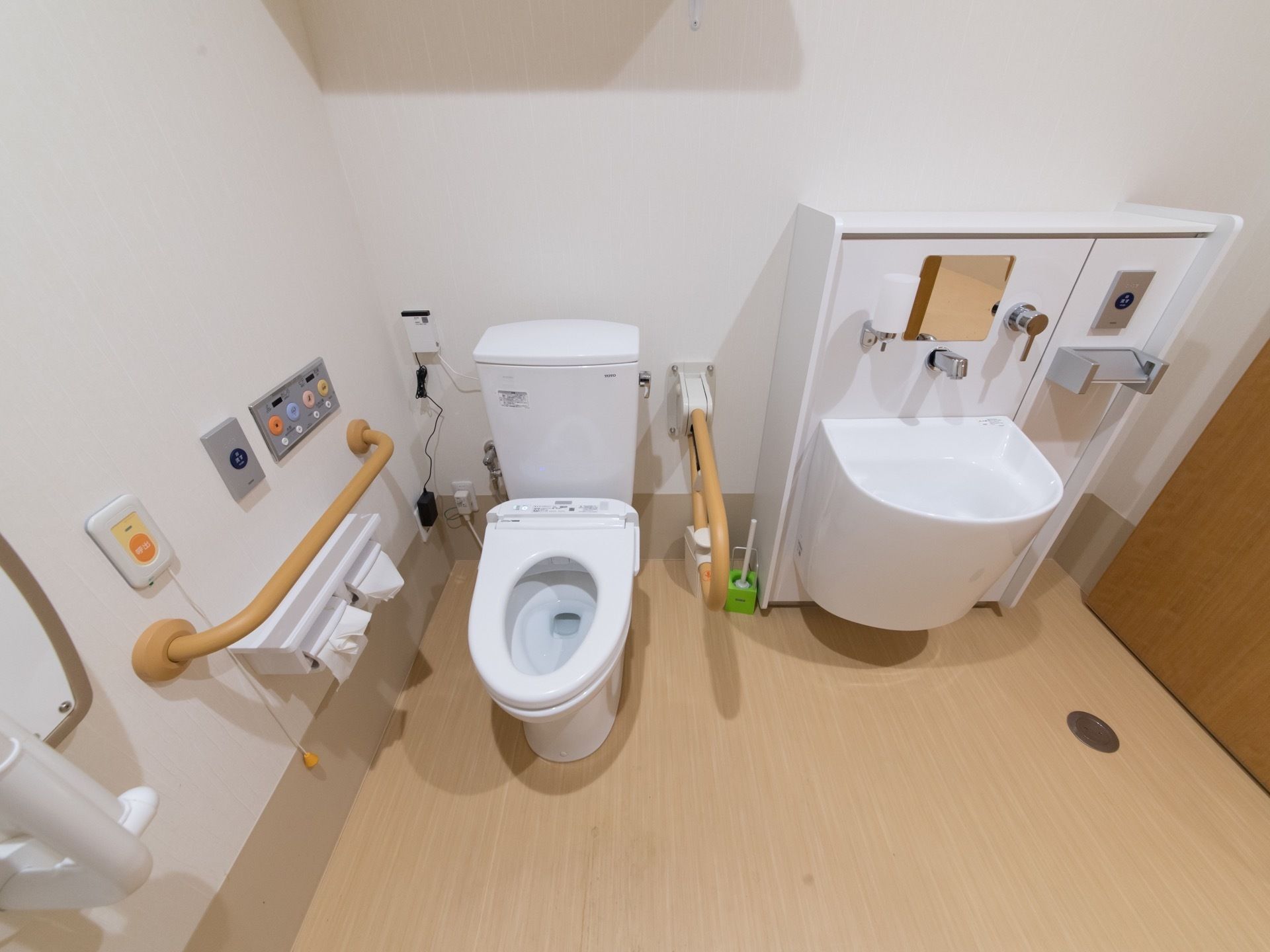 広い個室に、洋式トイレとオストメイト対応トイレが設置されている。間には可動式の手すりが設置されている。