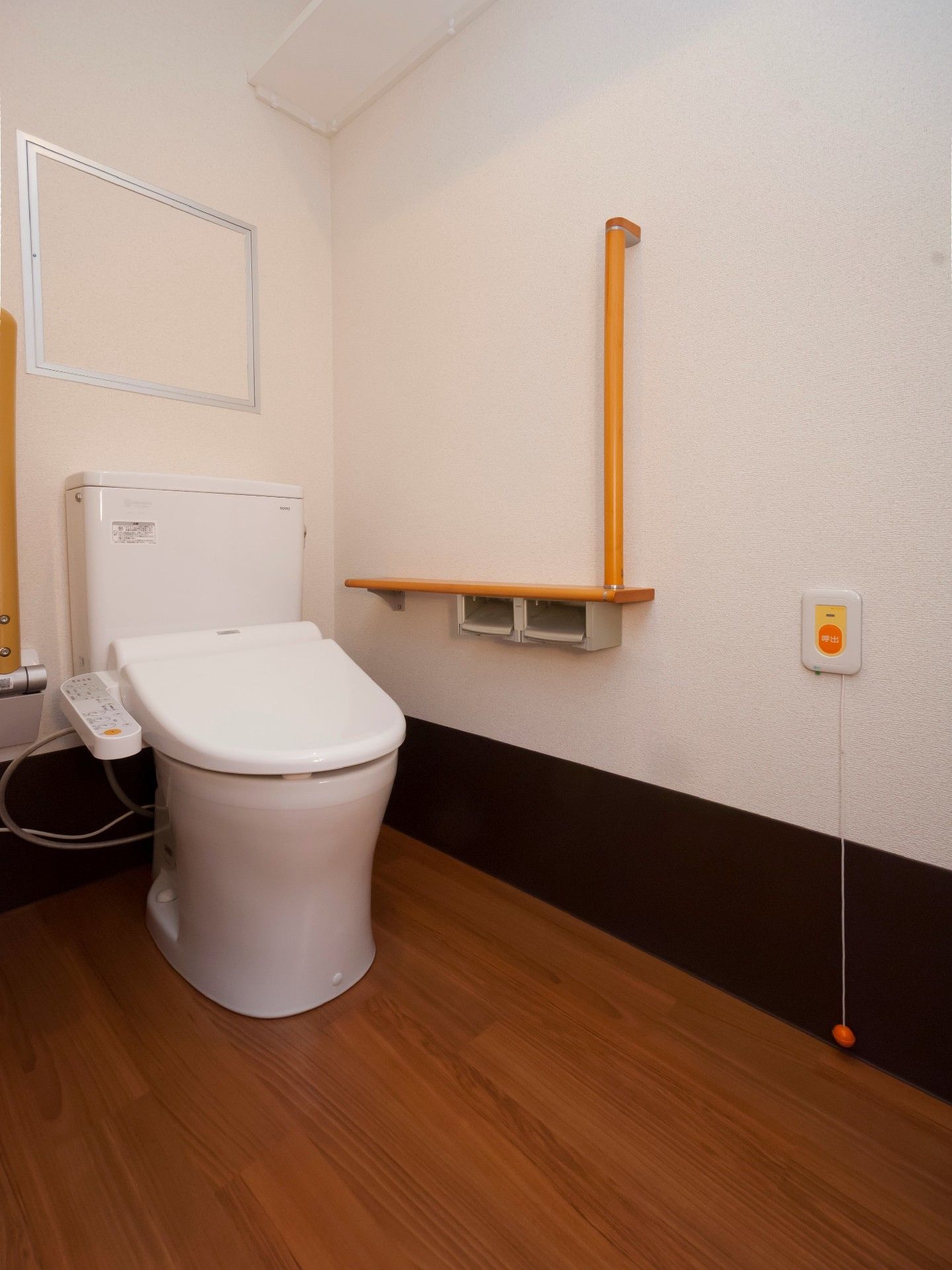 トイレットペーパーホルダーの上は物置台になっていて、近くには手すりが取り付けられている。スタッフの呼び出しボタンが設置されている。