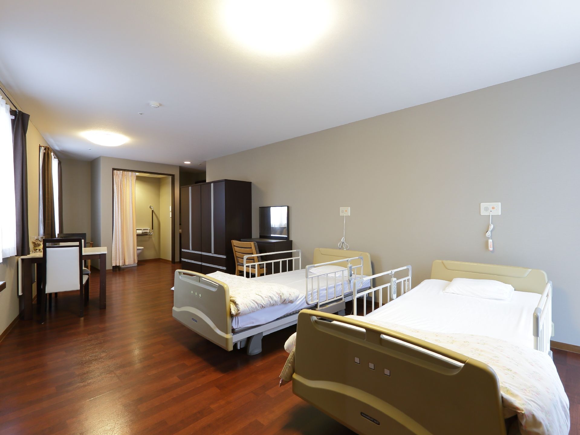 夫婦用の二人部屋には、リクライニング機能がついた介護用ベッドが2台用意されている。また壁には緊急時の呼び出しボタンが用意されている。